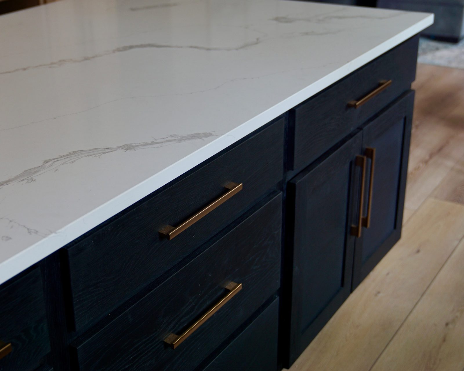 Centerville island detail — dark cabinetry with quartz top and brass pulls